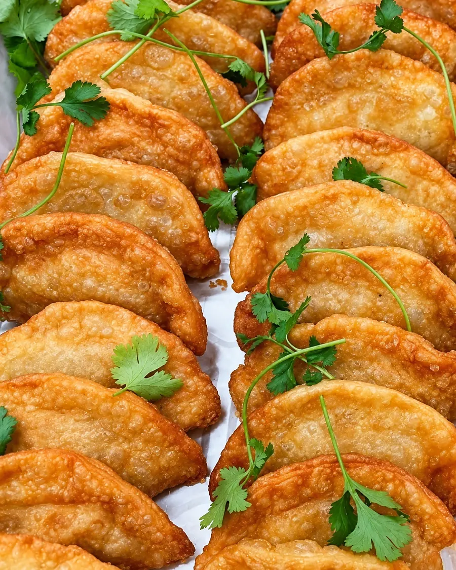 Catering tray of golden fried empanadas garnished with cilantro